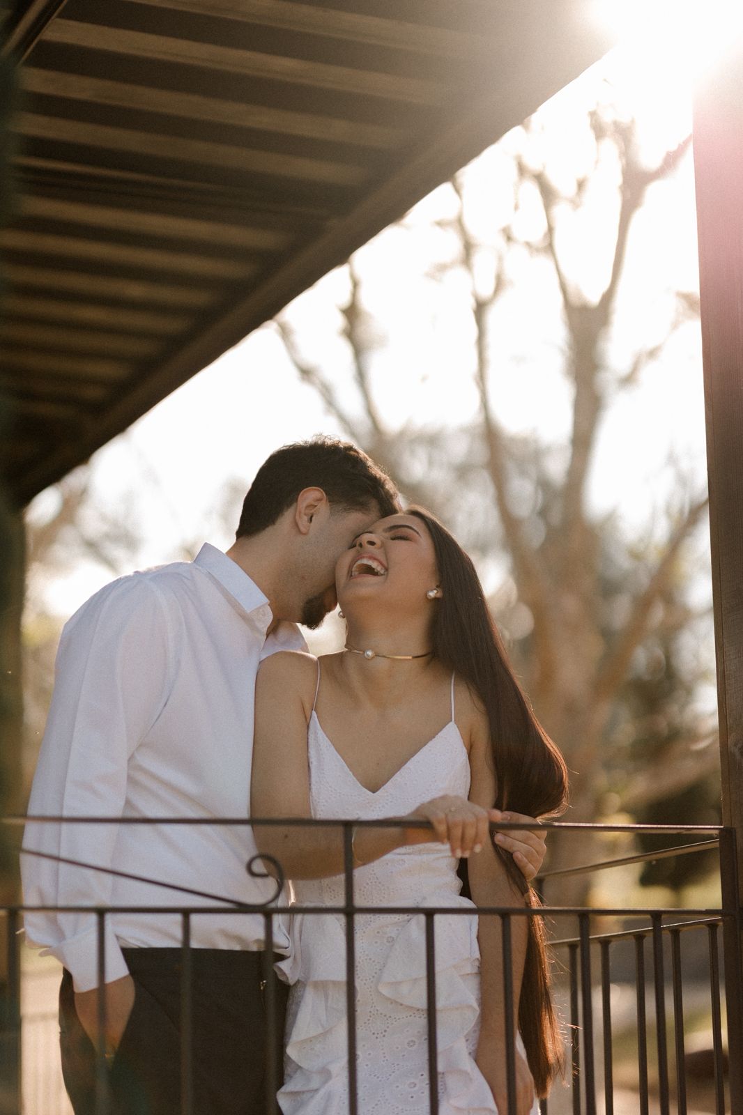 Casal sorrindo na varanda ao pôr do sol